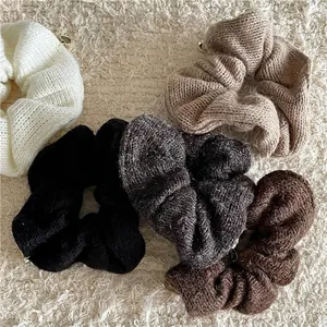 Cinq chouchous en tricot avec pendentifs cœur doré sur fond en peluche blanche