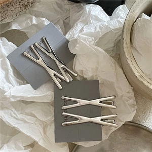 Dettaglio di quattro fermagli per capelli in lega argento opaco con finitura spazzolata