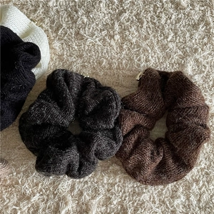 Gros plan de chouchous en maille blanc noir et marron avec pendentifs cœur dorés