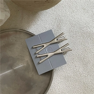 Dettaglio di fermagli per capelli in metallo argento a X con texture spazzolata
