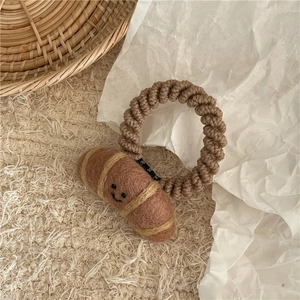 Close-up of wool felt croissant hair tie on beige fabric with a creative design