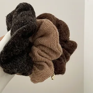 Trois chouchous en tricot aux tons terre avec un petit pendentif en forme de cœur doré