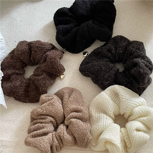 Vue à plat de cinq chouchous tricotés aux tons terreux avec pendentifs en forme de cœur