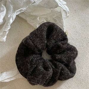 Vue macro d'un chouchou en tricot marron foncé avec laine douce et design élastique