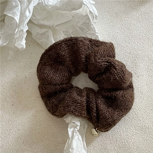 Gros plan sur chouchou tricoté marron avec texture en laine et pendentif cœur doré