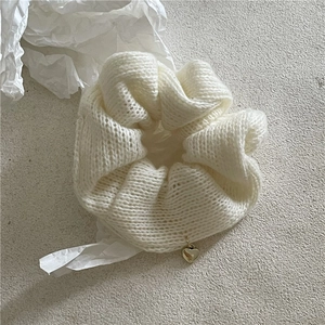 Gros plan du chouchou en tricot blanc avec un délicat pendentif en forme de cœur doré