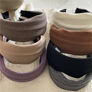 Set of wide padded fabric headbands in six matte colors on a rustic beige linen background