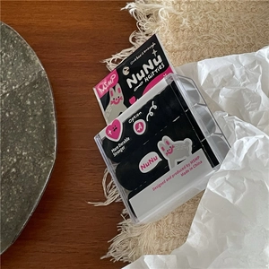 Detailopname van zwarte haarelastiekjes in een konijnenbox op een houten bureau