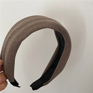 Detail of a wide brown fabric headband showing matte wool texture and non-slip lining