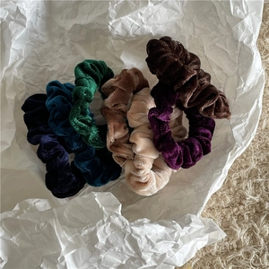 Macro detail of velvet scrunchies in vintage colors on a minimalist textured background