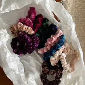 Set of colorful velvet scrunchies in various shades on white paper packaging
