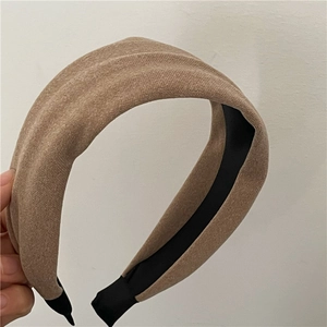 Close-up of wide beige fabric headband showing textured woven wool and black inner lining