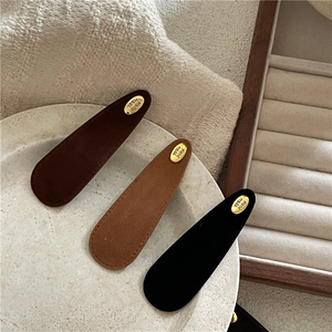 Three teardrop velvet snap hair clips in brown and black with gold metal accents