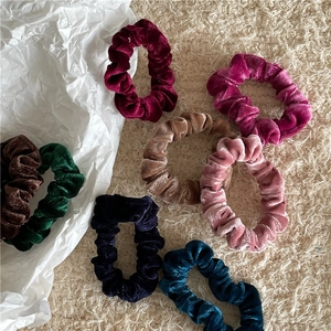 Macro shot of assorted velvet scrunchies with pleated texture on a neutral background