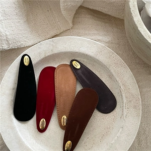 Detail of five teardrop velvet hair clips in assorted colors with gold handmade labels