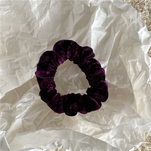 Detailed view of the dark purple velvet scrunchie with a soft ribbed texture