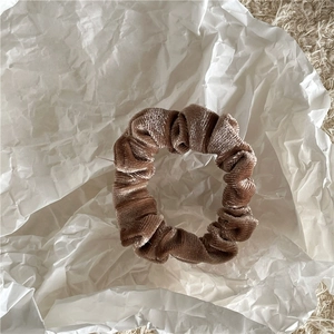Macro detail of dark apricot velvet scrunchie with striped texture for hair
