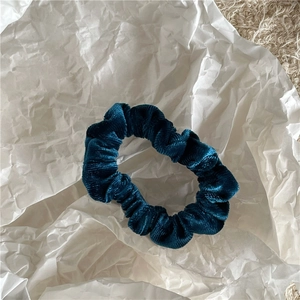 Close-up of velvet peacock blue scrunchie showing soft texture and pleated design