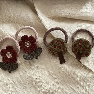 Macro detail of handmade crochet flower and cherry tree hair ties on linen fabric