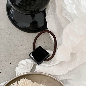 Détail d'un élastique à cheveux café avec motif carré noir et texte Creation France