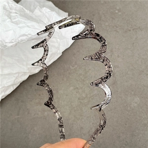 Close-up of wavy toothed resin headband with black ink marble texture detail
