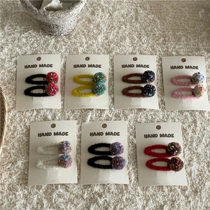 Detailed view of handmade knitted colorful pom pom hair clips on soft beige wool background