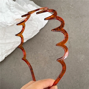 Close-up of stylish amber wavy headband featuring unique black branch-like textures