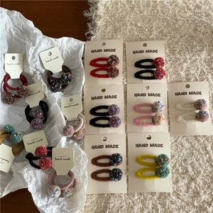 Handmade colorful pom pom hair clips and ties set on a cozy plush background display