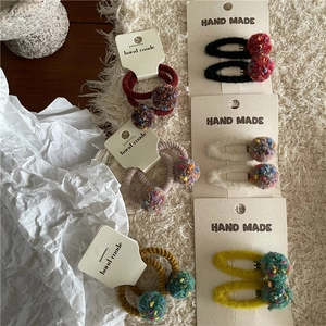 Detailed view of colorful plush pompom hair clips and elastic ties on handmade cards