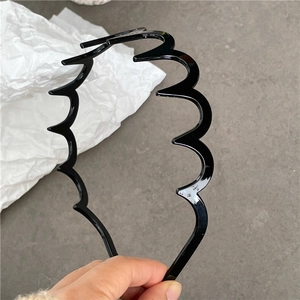 Detail view of black wavy zigzag plastic headband with glossy finish for hair styling