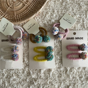 Close-up of colorful handmade plush ball hair clips and elastics on display cards