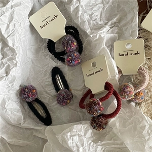 Close-up of handmade colorful fuzzy ball hair clips and elastics on card board