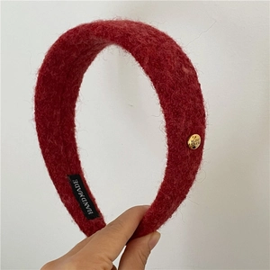 Détail du serre-tête en laine rouge avec étiquette fait main et boucle en métal