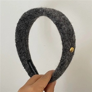 Détail de la texture du bandeau en laine grise avec breloque dorée et étiquette fait main