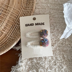 Detailed macro view of handmade colorful woven yarn balls on soft plush hair clips