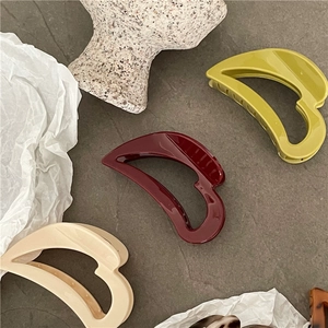 Close-up of elegant hollow heart hair claws in deep red, avocado green, and cream white