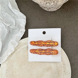 Détail des barrettes à cheveux ondulées motif ambre sur une carte de présentation