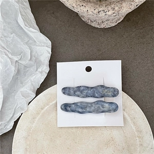 Vue détaillée de barrettes à cheveux ondulées effet marbre bleu sur assiette céramique