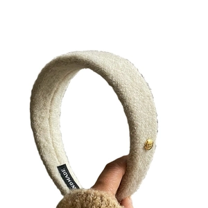Bandeau à cheveux en peluche blanc crème avec bouton doré gravé sur fond blanc épuré