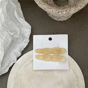 Gros plan de barrettes à cheveux ondulées en acétate ambre et crème sur carte