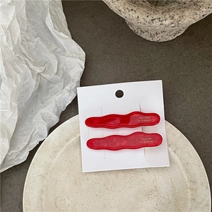 Détail macro de barrettes à cheveux rouges en acétate avec texture marbrée chic