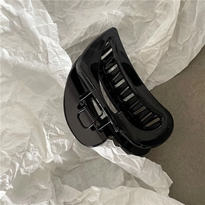 Detailed view of glossy black hair claw clip featuring elegant minimalist curved design