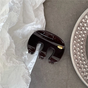 Détail d'une pince à cheveux marron foncé brillante avec une plaque dorée gravée