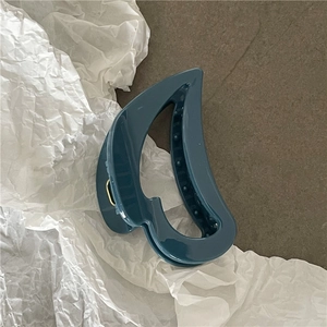 Macro view of dark blue hair claw clip with cutout heart design and glossy finish