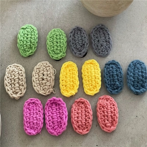 Flat lay of colorful oval knitted hair clips in cream shades on a grey textured surface