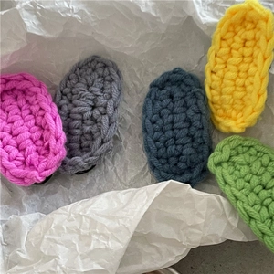 Detail of five-color hand-knitted oval hair clips in pastel pink, yellow and blue