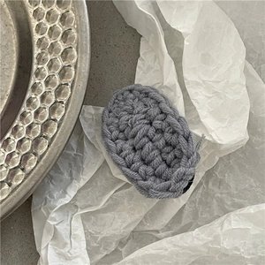 Detail of grey knitted oval BB hair clip showing the woven texture and metal base