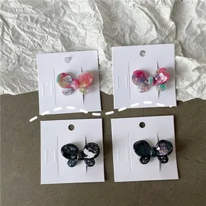 Detailed macro view of four acetate butterfly hair clips with iridescent colorful textures