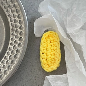 Macro detail of yellow knit crochet hair clip showing thick woven texture and oval shape