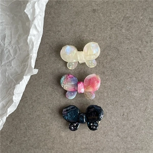 Detail of three acetate butterfly hair clips with shimmering finish and rhinestone accents